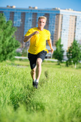 Sporty man jogging in city street park. Outdoor fitness.