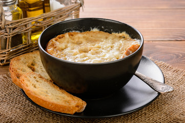 French onion soup with toasts on wooden table.