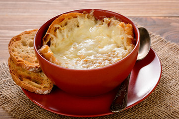 French onion soup with toasts on wooden table.