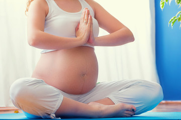 Pregnancy yoga. Young pregnant woman doing yoga at home.