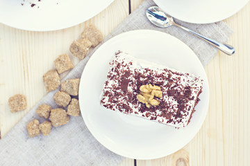 Delicious chocolate cake on plate on table on light background. Tonned photo.