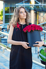 Girl with Bouquet of red roses in a box on the street