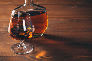 Glasses of cognac and bottle on the wooden table.