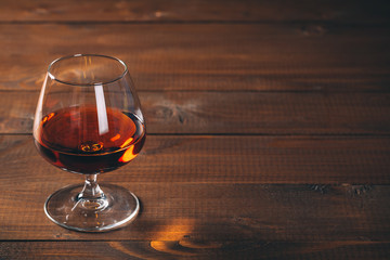 Glass of cognac on the wooden table.