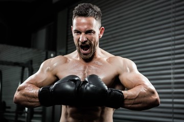 Obraz na płótnie Canvas Angry shirtless man with boxe gloves shouting