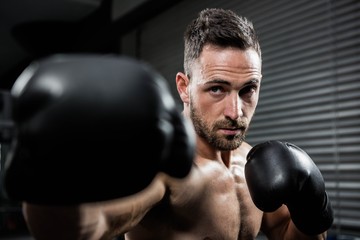 Determined shirtless man with boxe gloves hitting