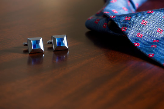 Cuff links and tie on mahogany wooden background