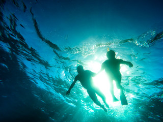Silhouette of senior couple swimming together in tropical sea - Snorkeling tour in exotic scenarios - Concept of active elderly and fun around the world - Soft focus due to backlight and water density - obrazy, fototapety, plakaty
