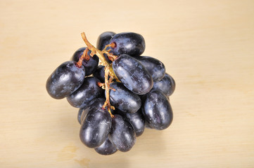 Delicious and fresh black seedless grape on wood plank