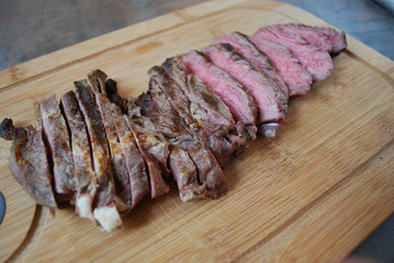 Chopped grilled beef steak on wooden board.
