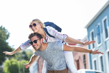 Hip man giving piggy back to his girlfriend