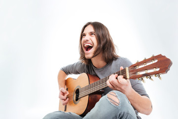 Happy young man with long hair playing guitar and singing