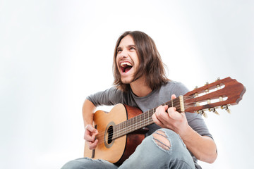 Fototapeta premium Happy young man with long hair playing guitar and singing