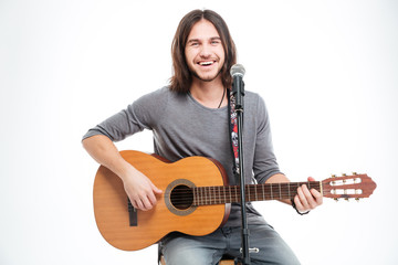 Obraz premium Smiling handsome young man with guitar singing in microphone