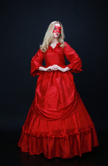 full length portrait of a beautiful blonde woman wearing a historical red silk, victorian era ball gown.