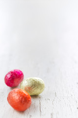 Small chocolate Easter eggs on a rustic white background