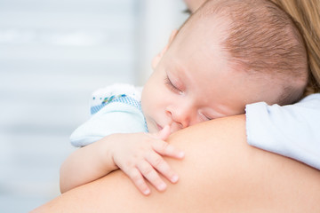 Obraz na płótnie Canvas Cute baby sleeping on his mother's shoulder