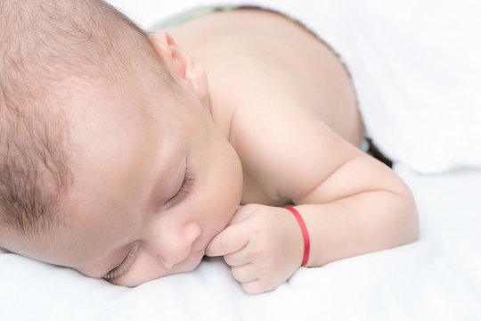 picture of a newborn baby curled up sleeping on a blanket