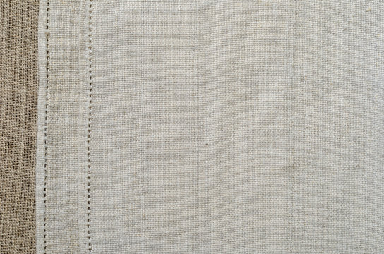 Background of the ancient homespun fabric with a handmade hem