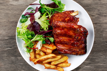 Roasted Pork Rib,  Fried Potato on white plate with Vegetables.