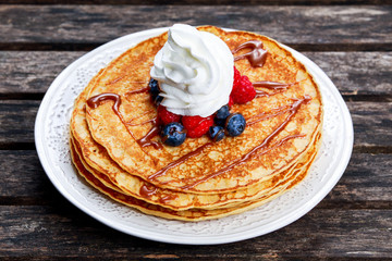 Fresh golden pancakes with cream and chocolate, fruit