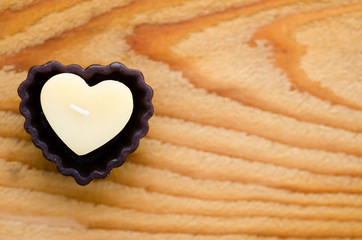 Heart shaped candle on wooden background