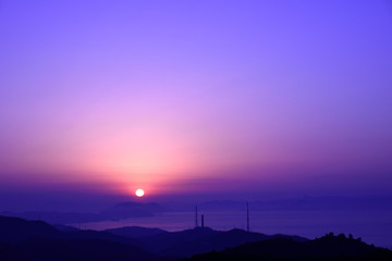 海と日の出と煙突