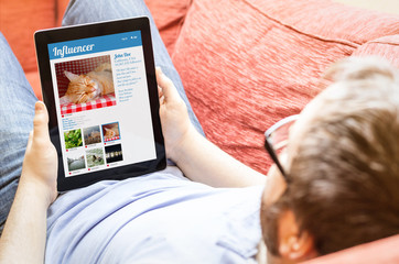 hipster on the sofa with influencer marketing tablet