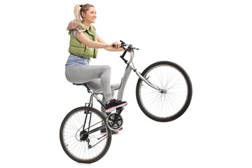 Young woman doing a wheelie on a bicycle