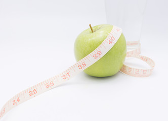 A green apple with a measuring tape wrapped around it for the co