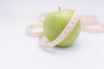 A green apple with a measuring tape wrapped around it for the co
