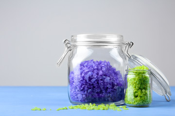 fragrant purple and green sea salt is in a glass jar with lid on a blue wooden table