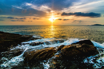 Seaside with stone and colorful sky at sunset.
