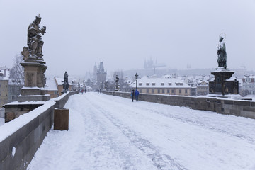 Fototapeta na wymiar Snowy foggy Prague Lesser Town with gothic Castle from Charles Bridge, Czech Republic