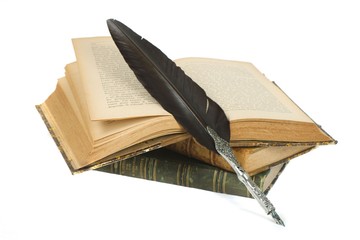 Quill pen resting on a pile of old books isolated on white background
