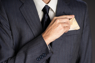 Business man in suit putting banknotes  (fifty euros) in his jacket breast pocket