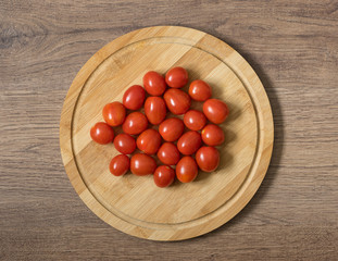 Fresh raw tomatos food. Red cherry tomatoes on the bamboo cutting board. Brown wood imitating background