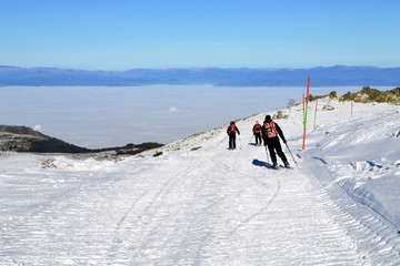 Three skiers descend from mountain peak, Cherni Vrah, Vitosha Mountain, Bulgaria