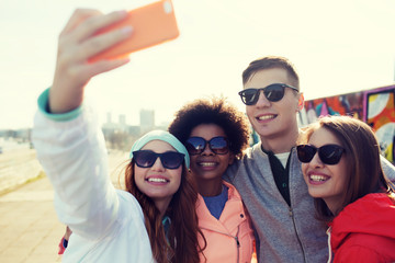 smiling friends taking selfie with smartphone