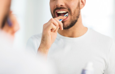 close up of man with toothbrush cleaning teeth