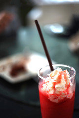 Strawberry smoothie with whip cream is on the table.