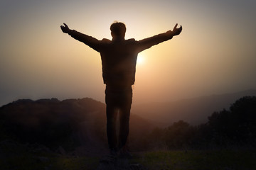 Man with arms raised at sunset on the mountain