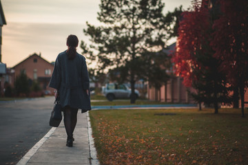 young woman in grey coat walking down the street,autumn. The view from the back 