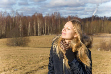 Happy, young girl sunbathing her face in sunny spring and breathing fresh air