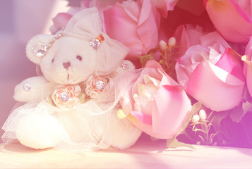 Fototapeta na wymiar Teddy bear girl white with pink roses bunch, soft focus.