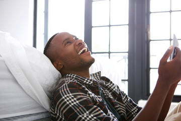 Cheerful young african man sitting at home with a digital tablet