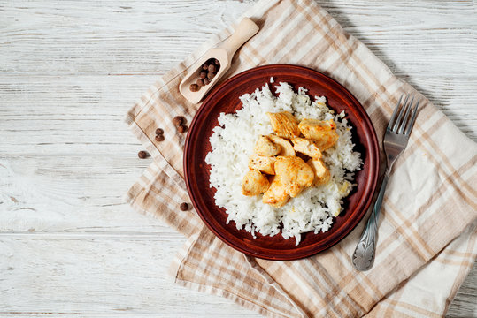  food, steamed rice with chicken breast , fried in spices and pepper on a wooden background
