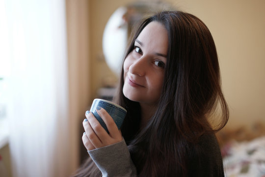 Молодая женщина пьёт чай из голубой чашки