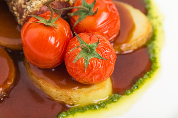 Tomatoes confit and baked potatoes close up.