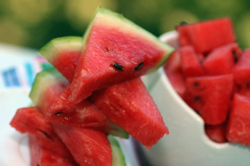 slices of watermelon in a bowl on a blurred background